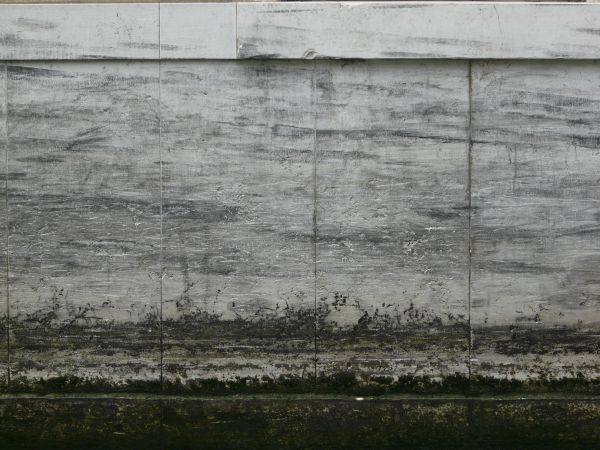 White cement wall with grey streaks and algae on bottom.